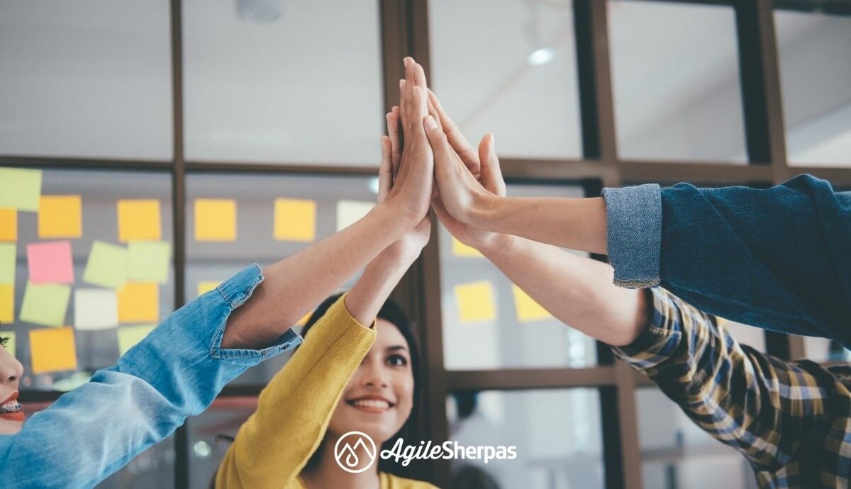 A team in front of a Kanban board giving each other high-five