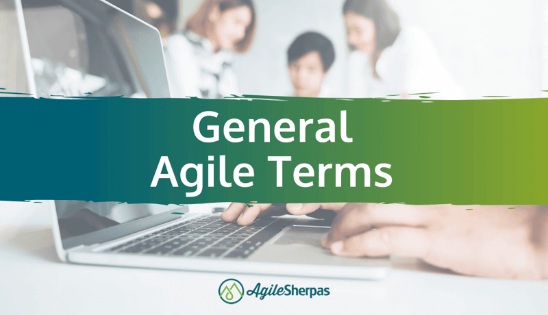 A banner saying "general Agile terms" infront of a person typing on a laptop surrounded by colleagues in the backgrond.
