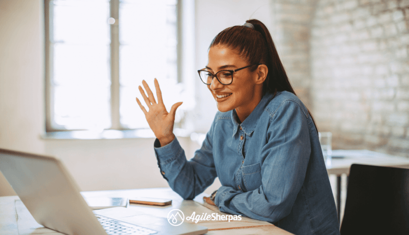 Young female professional waving at a laptop screen