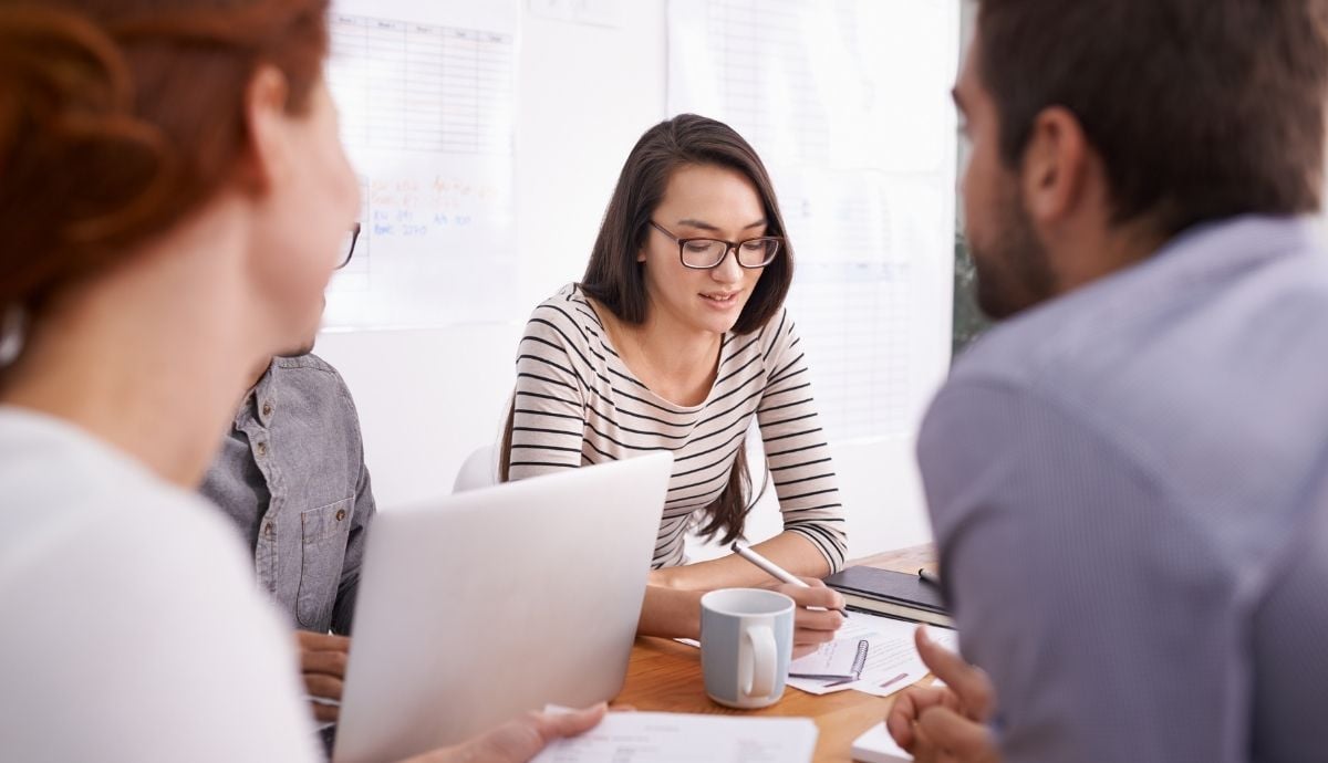 A team in a meeting with a woman taking notes in the center.