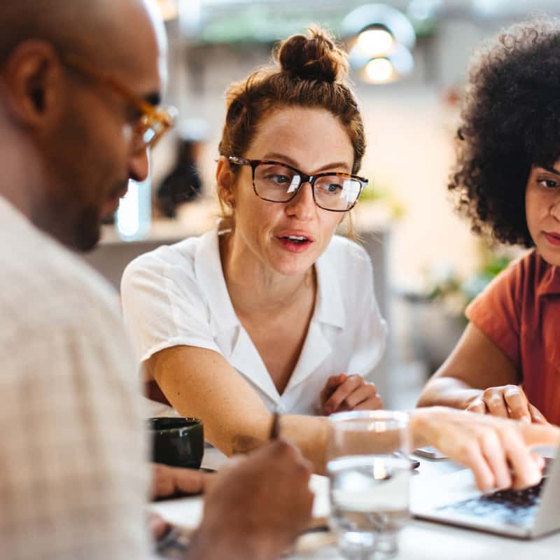 woman-pointing-out-information-on-a-screen-to-her-coworkers-400x400