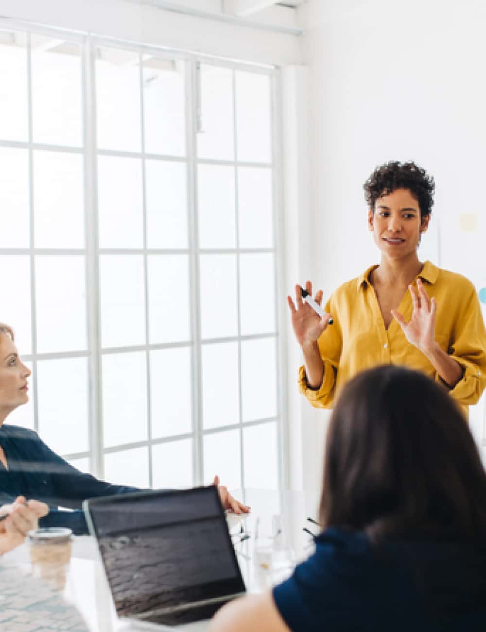 woman-standing-at-whiteboard-in-meeting-500x650
